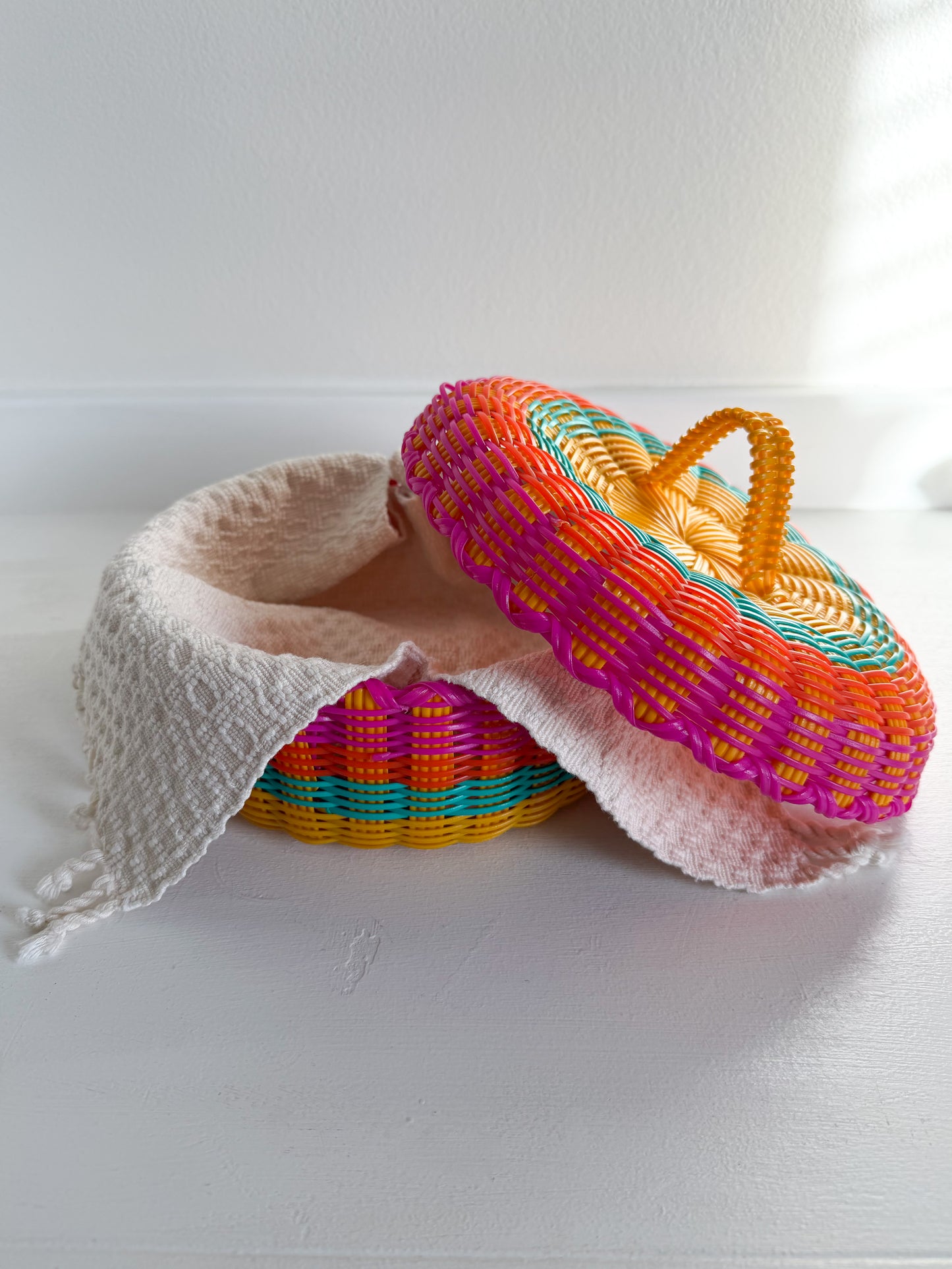 Colorful woven basket with a pink interior on a white surface
