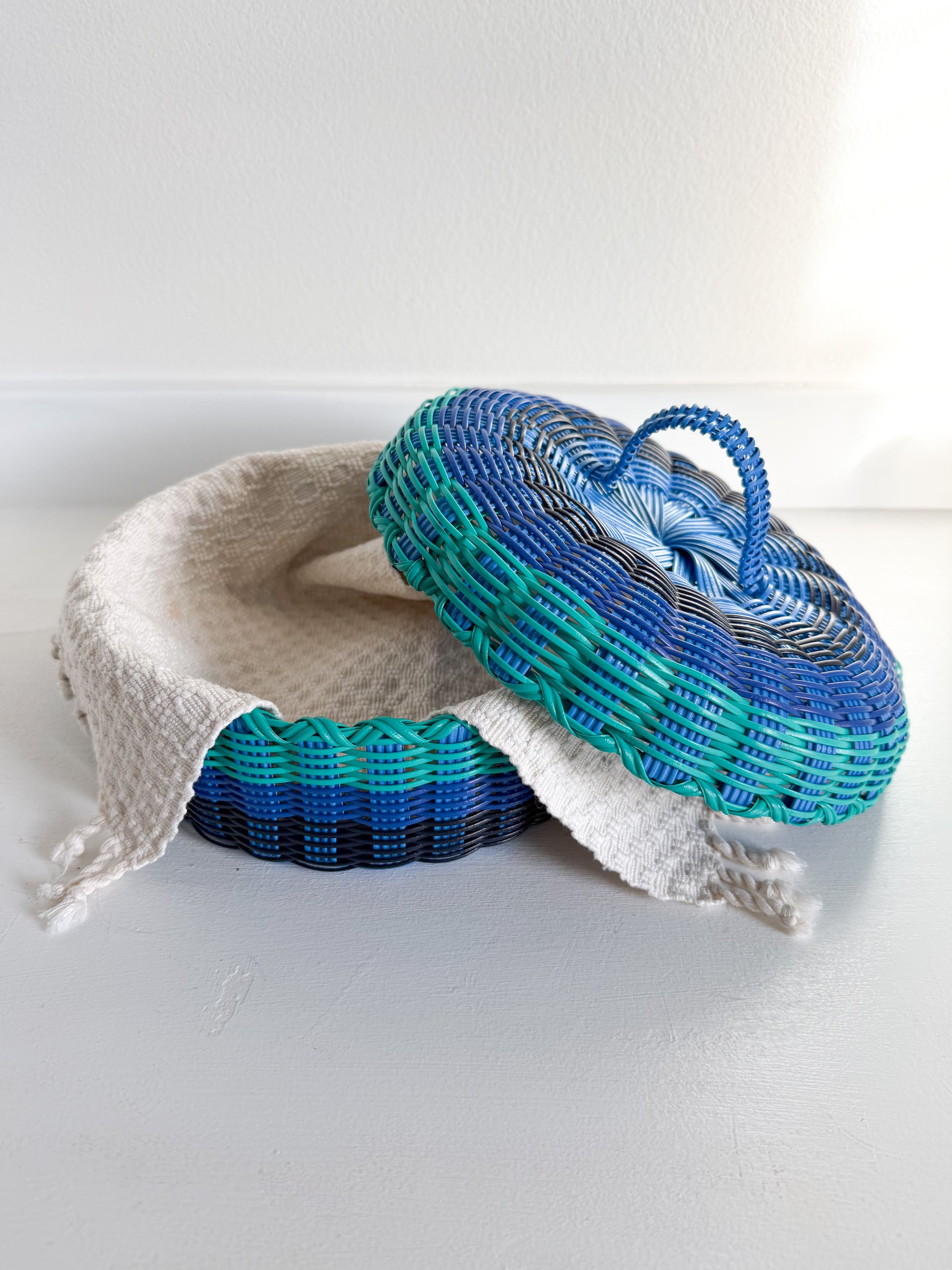 Two woven baskets, one white and one blue with a pattern, on a white background.